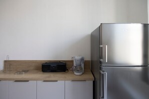 A kitchen with a stainless steel refrigerator, a coffee maker, and a Philips radio on a wooden countertop. - Cozy Apartment Place Paoli – Mountain View, Heart of Corte (Corte)