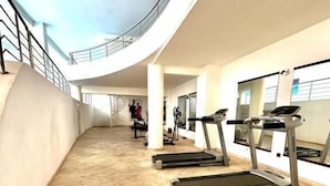 Un gimnasio amplio y moderno con cintas de correr, techo curvo y vistas al cielo.