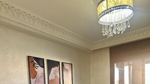 Una sala de estar con un sofá modular azul, una araña y tres obras de arte enmarcadas en la pared.