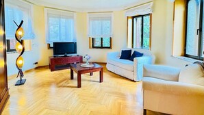 A living room with a sofa, a coffee table, a TV, and a decorative lamp. - Room 'Suite Presidencial' with Shared Terrace, Wi-Fi and Air Conditioning (Guadarrama)