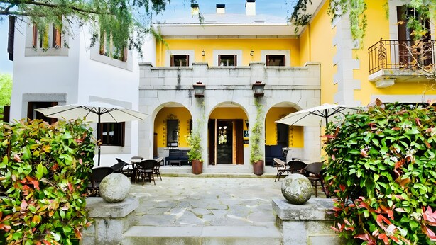 A courtyard with stone steps leading to a yellow building with arched doorways, outdoor seating, and potted plants. - Room 'Suite Presidencial' with Shared Terrace, Wi-Fi and Air Conditioning (Guadarrama)