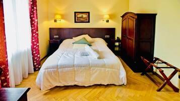 A hotel room with a large bed, two bedside lamps, a wooden wardrobe, and a wooden chair.