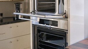 Une cuisine équipée d’un four à deux cavités, d’une machine à café et d’une plante posée sur une étagère.