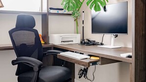 A modern office space with a desk, chair, computer monitor, keyboard, and a potted plant. - New Luxury Home in Koza | Work-Friendly | Free Parking (沖縄県)
