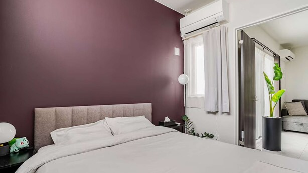 Een moderne slaapkamer met een groot bed, een nachtkastje, een lamp en een pot met een plant.
