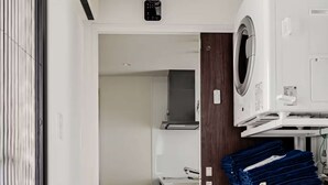Een wasserette met een witte wasmachine, droger en opgestapelde blauwe handdoeken.