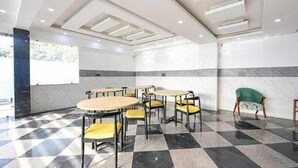 A conference room with checkered flooring, round tables, and chairs. - Hotel Vibe BLU (Noida)