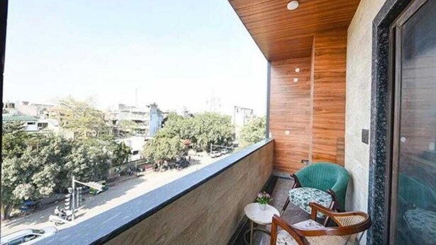 A balcony with a view of a cityscape, a small table, and two chairs. - Hotel Vibe BLU (Noida)