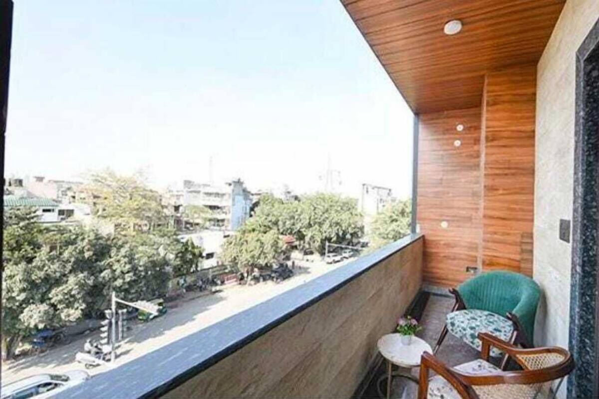A balcony with a view of a cityscape, a small table, and two chairs.