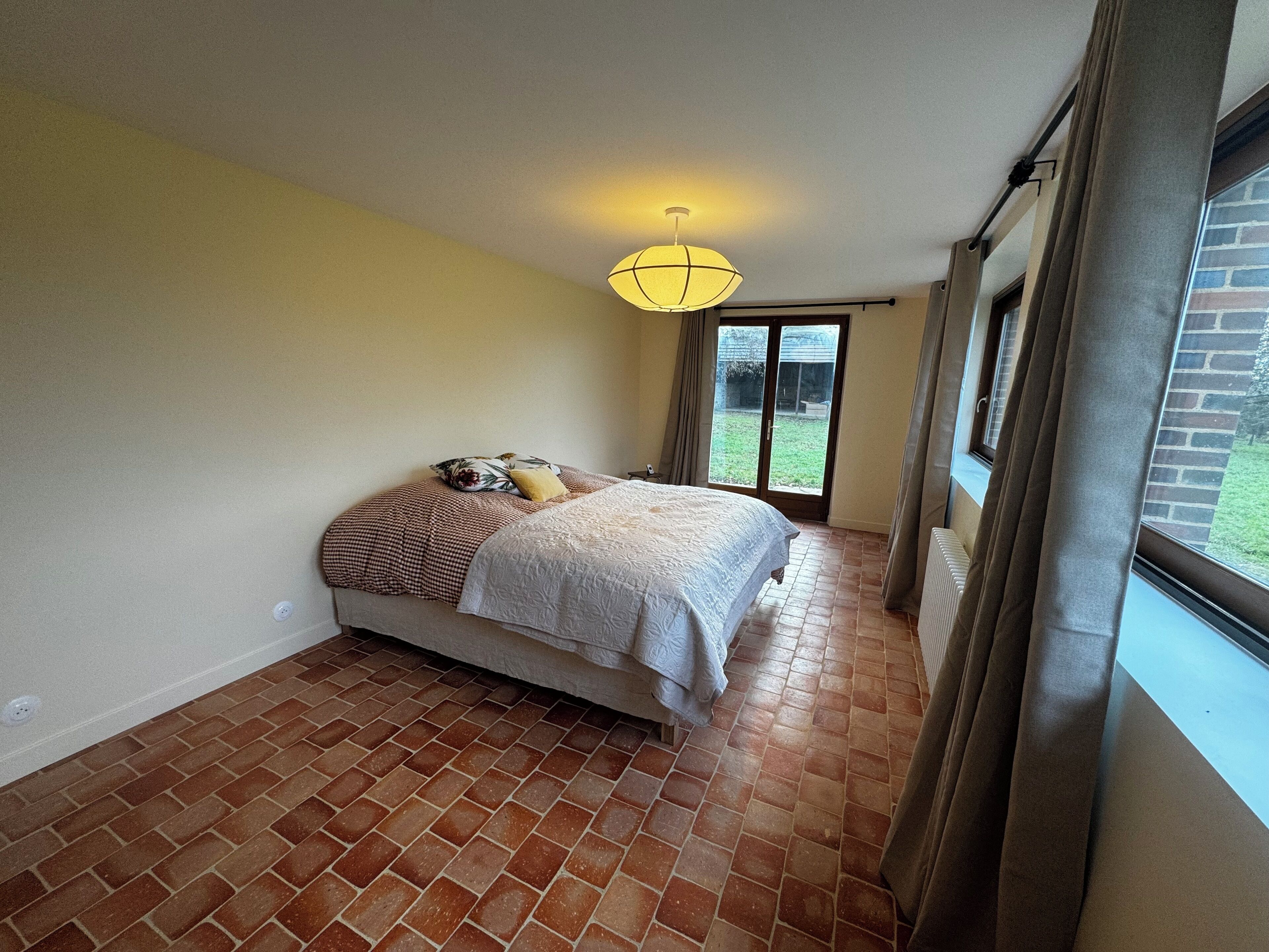 A bedroom with a bed, a ceiling light, a window, and a view of the outside.