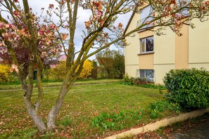 Ein Wohngebäude mit gepflegtem Rasen, blühenden Bäumen und einer Hecke.