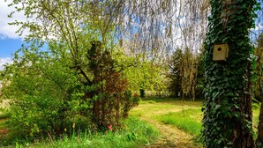 A natural outdoor setting with a path, trees, and a birdhouse. - Holiday Home "Villa for 8 Guests – Porte du Ried" with Mountain View, Private Terrace & Wi-Fi (porte du ried)