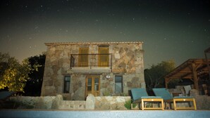 Un bâtiment en pierre doté d’un balcon, d’une piscine et de chaises longues.