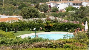 A residential area with a swimming pool, lush greenery, and houses with red-tiled roofs. - Hotiday Baja Sardinia Saline (Baja Sardinia)