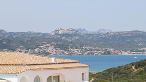 A coastal building with a tiled roof overlooking a sea and a mountainous landscape. - Hotiday Baja Sardinia Saline (Baja Sardinia)