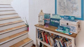 A staircase with a white wall, a framed map, and a shelf with books and holiday cards. - Hotiday Baja Sardinia Saline (Baja Sardinia)