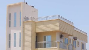 A multi-story residential building with balconies, air conditioning units, and a clear sky. - Prime Apartment Dalaba (Old-Yundum)