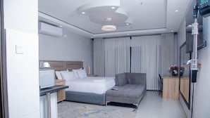 Habitació d'hotel moderna amb llit, sofà, escriptori i televisió.