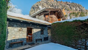 A stone building with a wooden balcony, a bench, and a snow-covered ground.