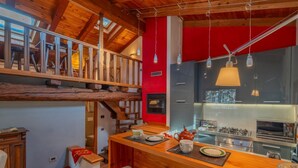 A modern kitchen with a wooden island, a red accent wall, and a lofted dining area.