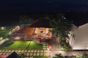 A two-story house with a wooden deck and a covered patio. - Rhythm Eco And Agro Stays (Mahabaleshwar)