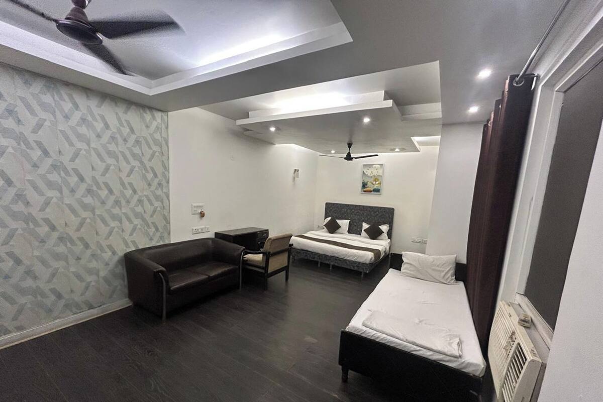 A modern hotel room with a bed, a sofa, a desk, and a ceiling fan.
