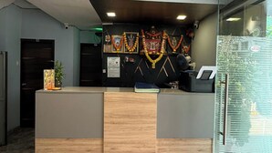 A reception desk with a marble floor, a glass partition, and a wall-mounted fan. - Hotel Stay Inn Rabale (Navi Mumbai)