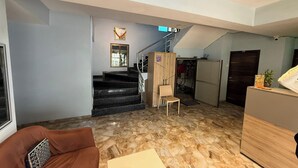 A living room with a brown sofa, a wooden cabinet, a staircase, and a small table. - Hotel Stay Inn Rabale (Navi Mumbai)