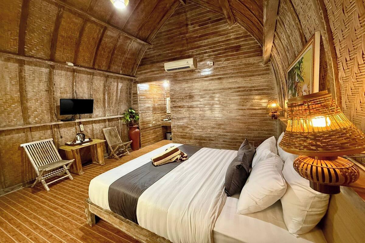 A rustic wooden room with a bed, a television, a table, and chairs.