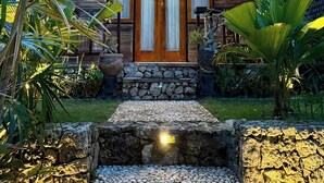 A wooden house with a stone staircase leading to the entrance, surrounded by tropical plants. - The Suwi Huts (Penida Island)