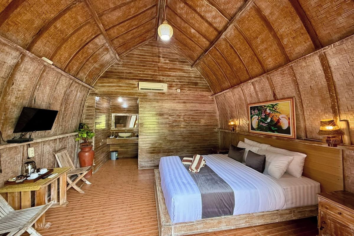 A rustic wooden room with a bed, a television, a desk, and a chair.