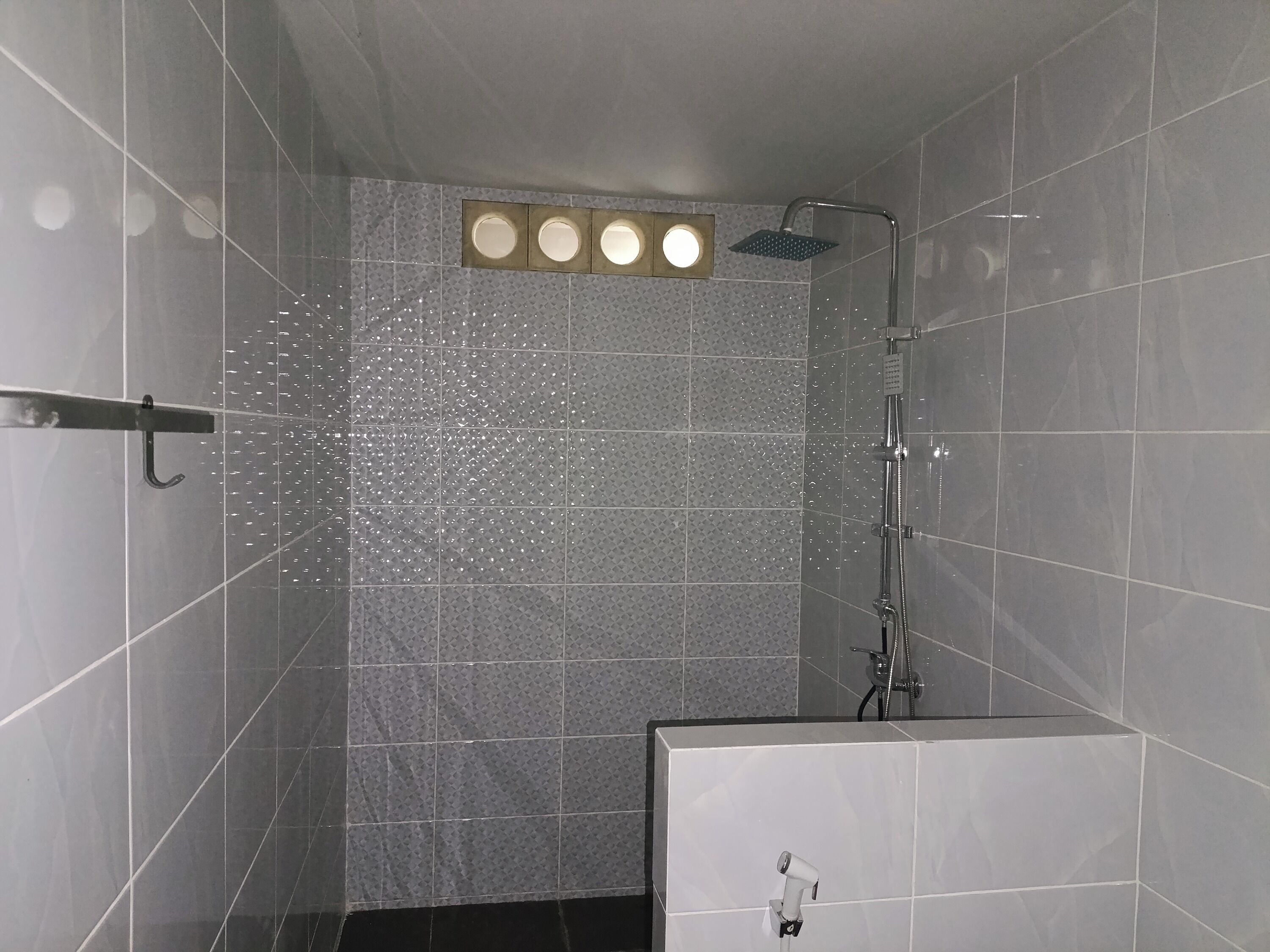 A modern shower area with a handheld showerhead and a fixed showerhead above a tiled wall.