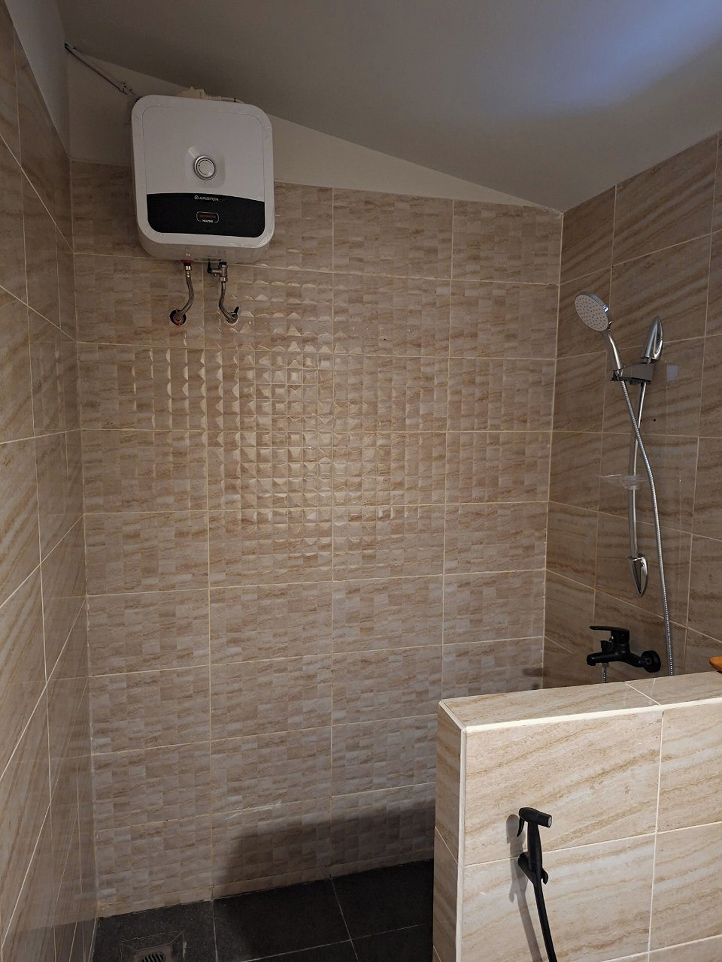 A bathroom with a shower, a toilet, and a wall-mounted heater.