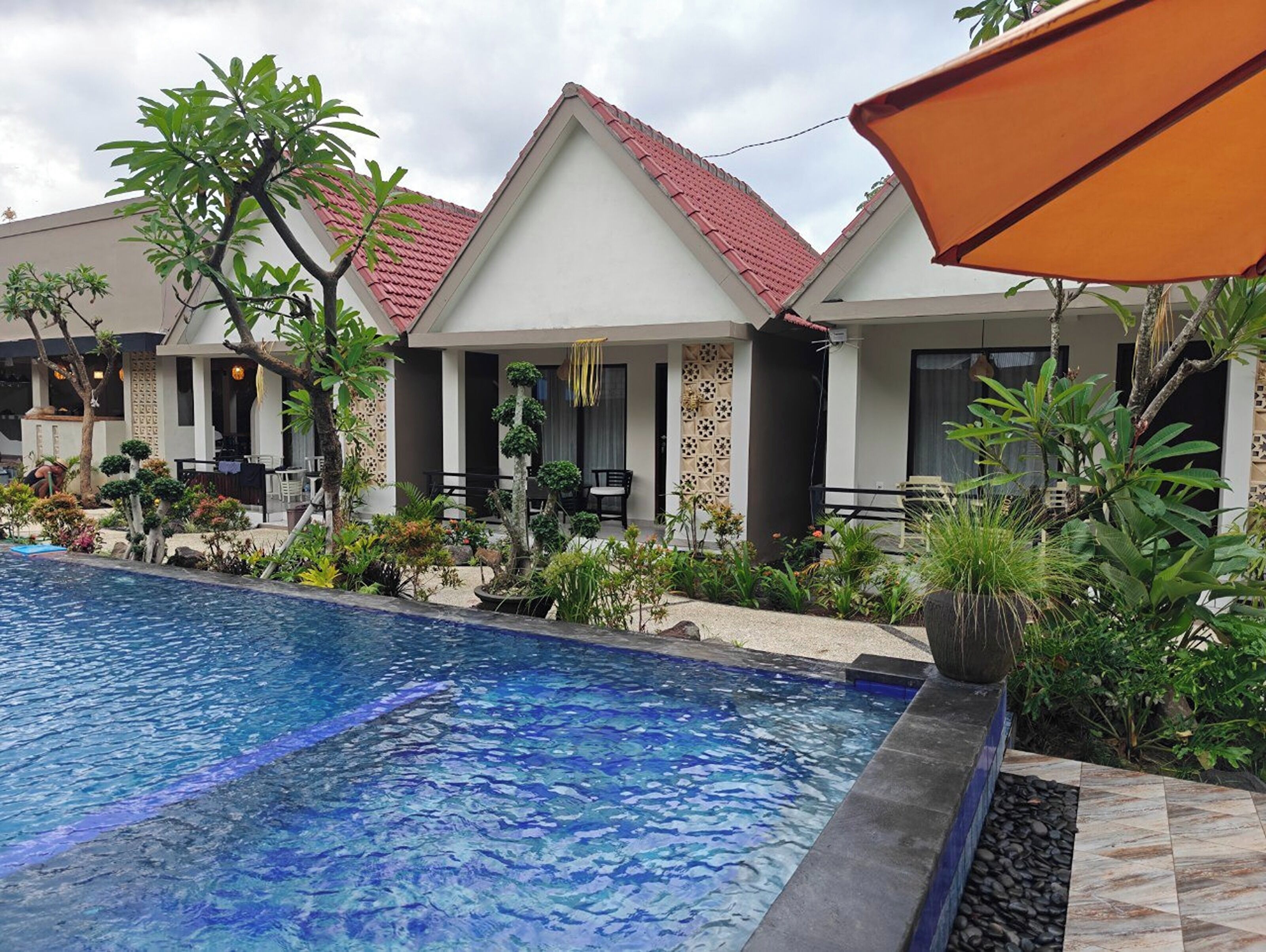 A modern hotel with a swimming pool, outdoor seating, and lush landscaping.