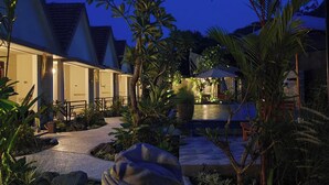 A resort with a pool area, palm trees, and a statue. - Ghangga Amed (Karangasem)