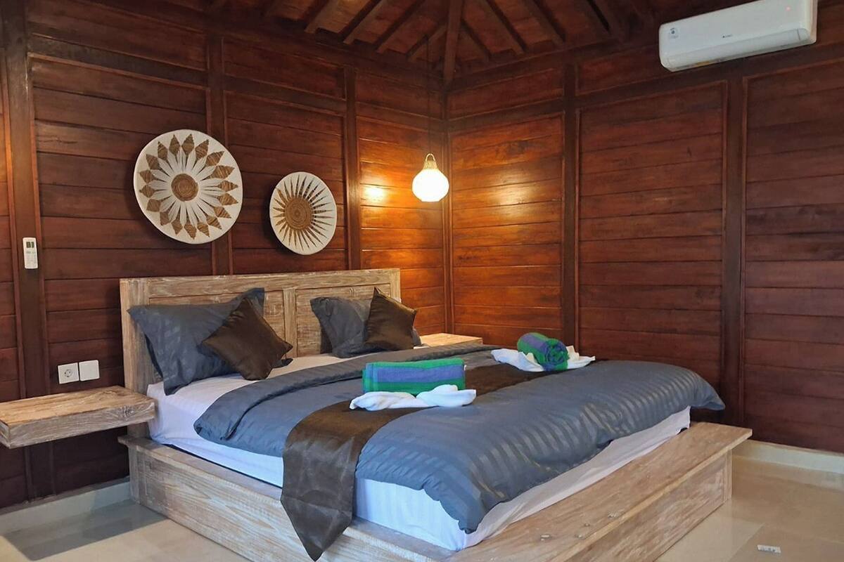 Une chambre à coucher aux murs lambrissés, avec un lit, des oreillers, une table de chevet et des éléments décoratifs sur les murs.