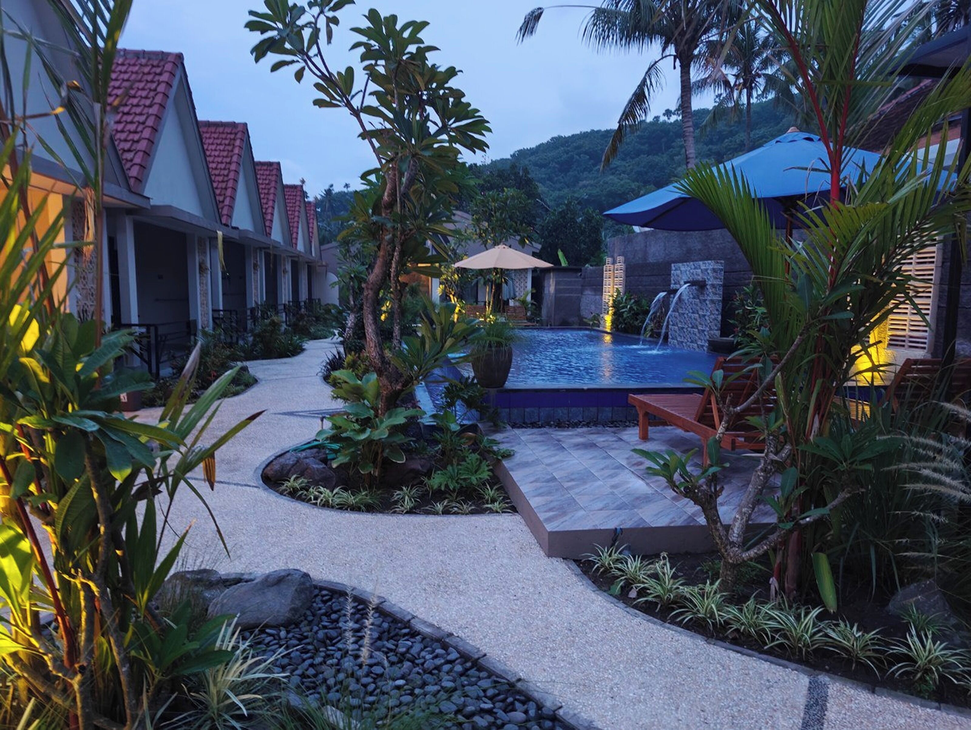 A resort with a swimming pool, palm trees, and a pathway leading to the pool.