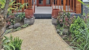 A wooden building with a thatched roof, a wooden porch, and a gravel pathway leading to the entrance. - Ghangga Amed (Karangasem)