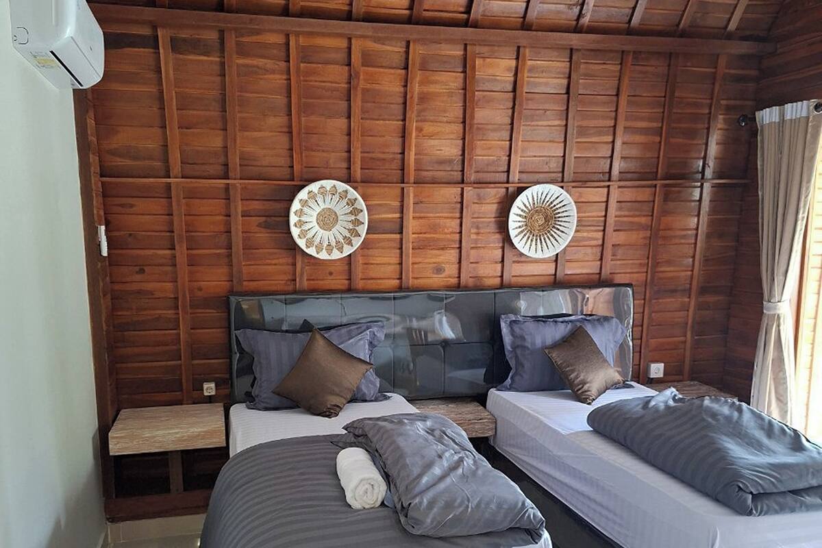 Une chambre avec deux lits, un lambris en bois au plafond et deux ventilateurs fixés au mur.