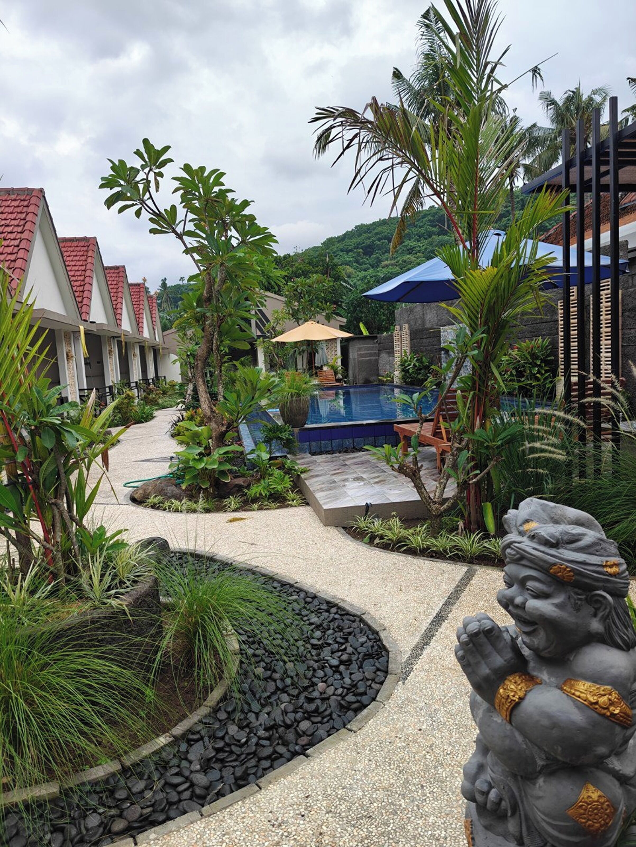 A resort with a swimming pool, palm trees, and a statue.