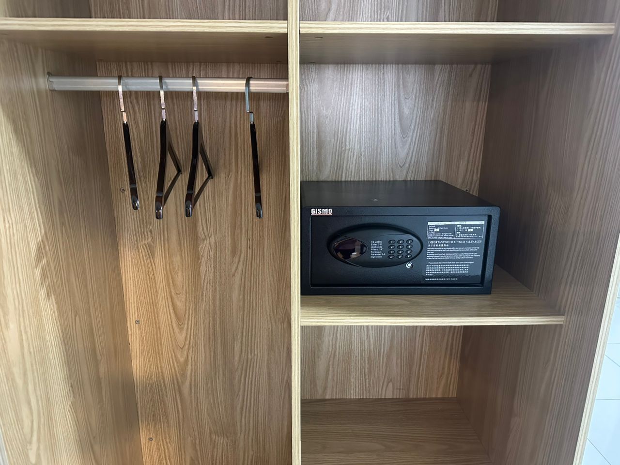 A wooden wardrobe with a black electronic device on the right shelf.
