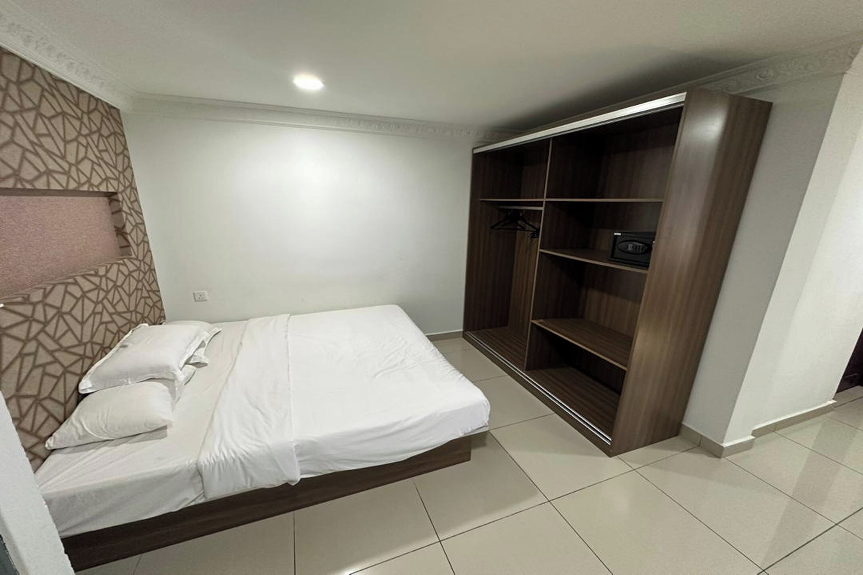 Ein Schlafzimmer mit Bett, Kleiderschrank und einer Wand mit Muster.