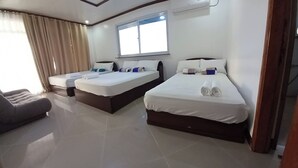 A hotel room with two beds, a sofa, and a large window. - Seven Waves Beachfront (Bauang)