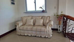A beige sofa with ruffled edges, a window above, and a decorative railing. - Seven Waves Beachfront (Bauang)