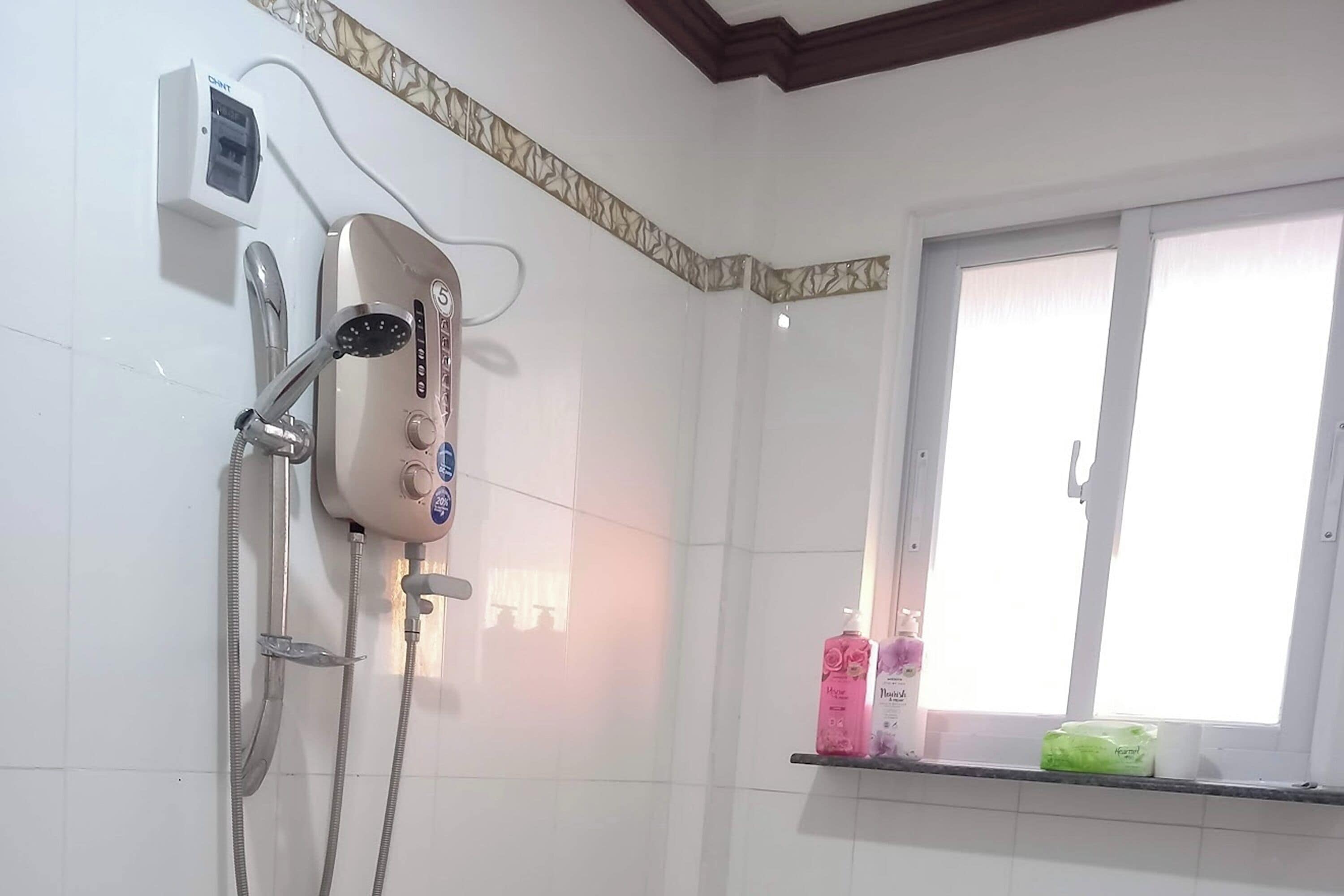 Kylpyhuone, jossa on suihku, ikkuna ja hylly, jossa on hygieniatuotteita.