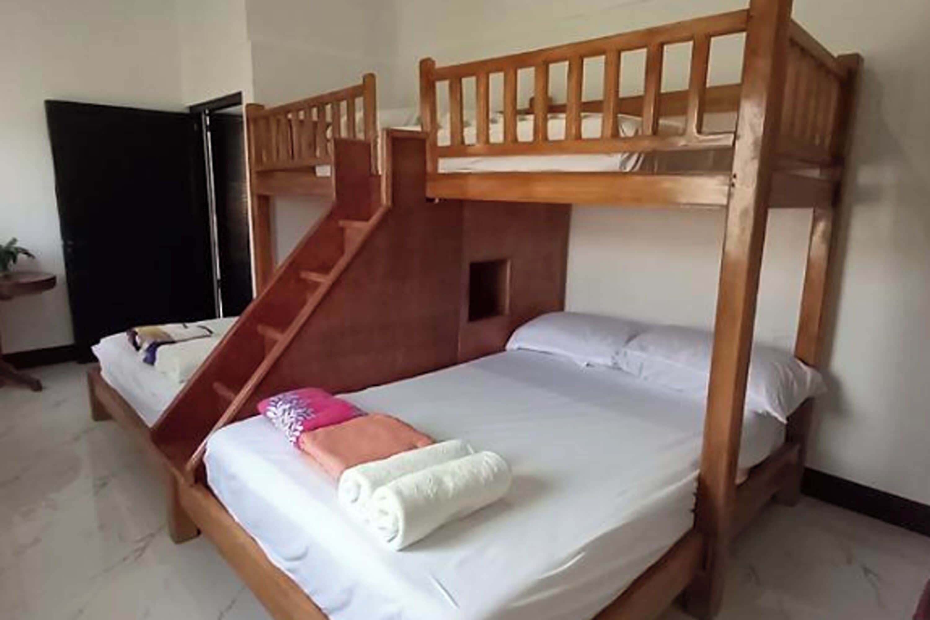 Un letto a castello con una scala in legno, una piccola finestra e una porta.