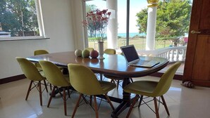 A dining area with a round table, six chairs, and a laptop. - Seven Waves Beachfront (Bauang)