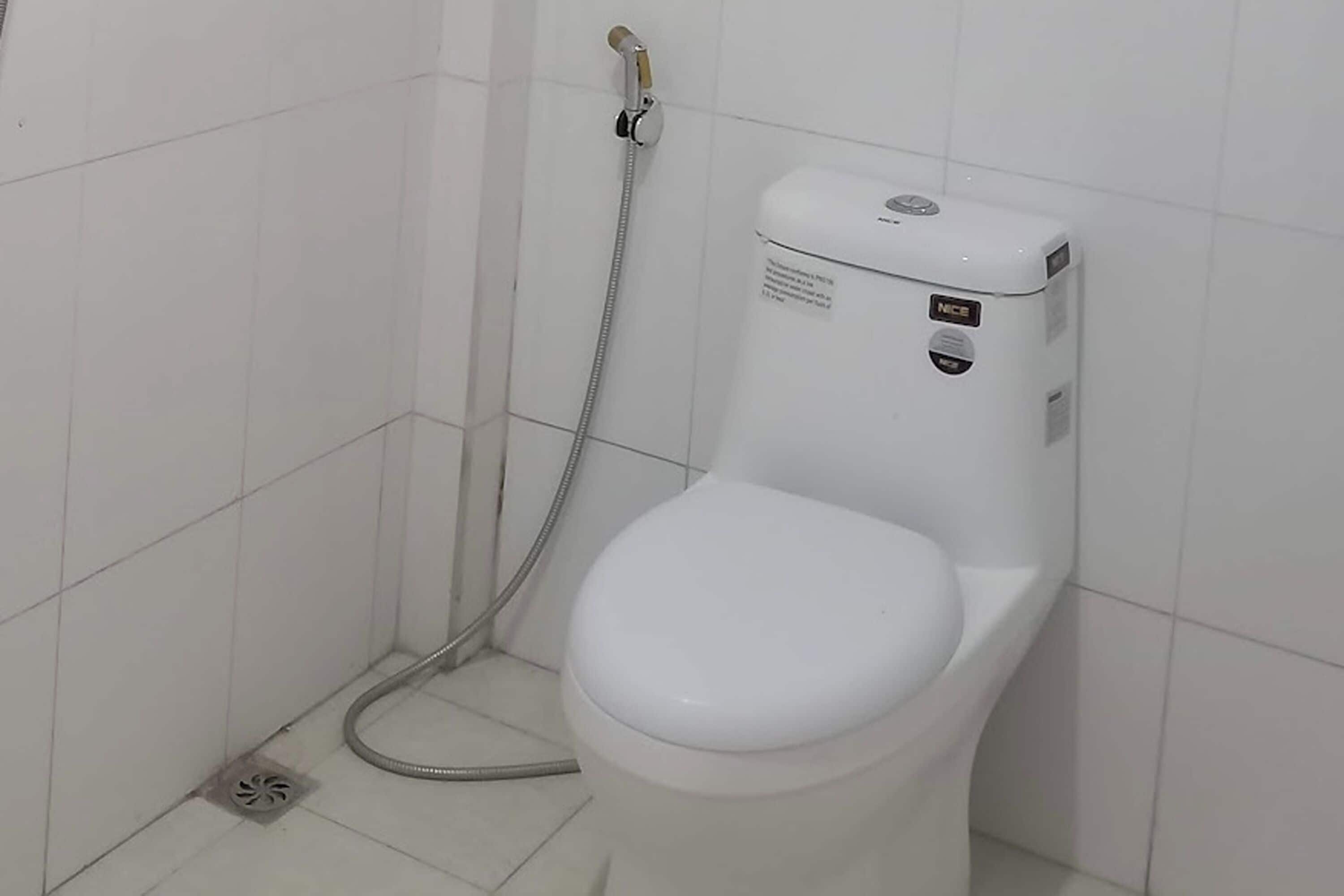Eine weiße Toilette mit Bidetfunktion und einer Handbrause.