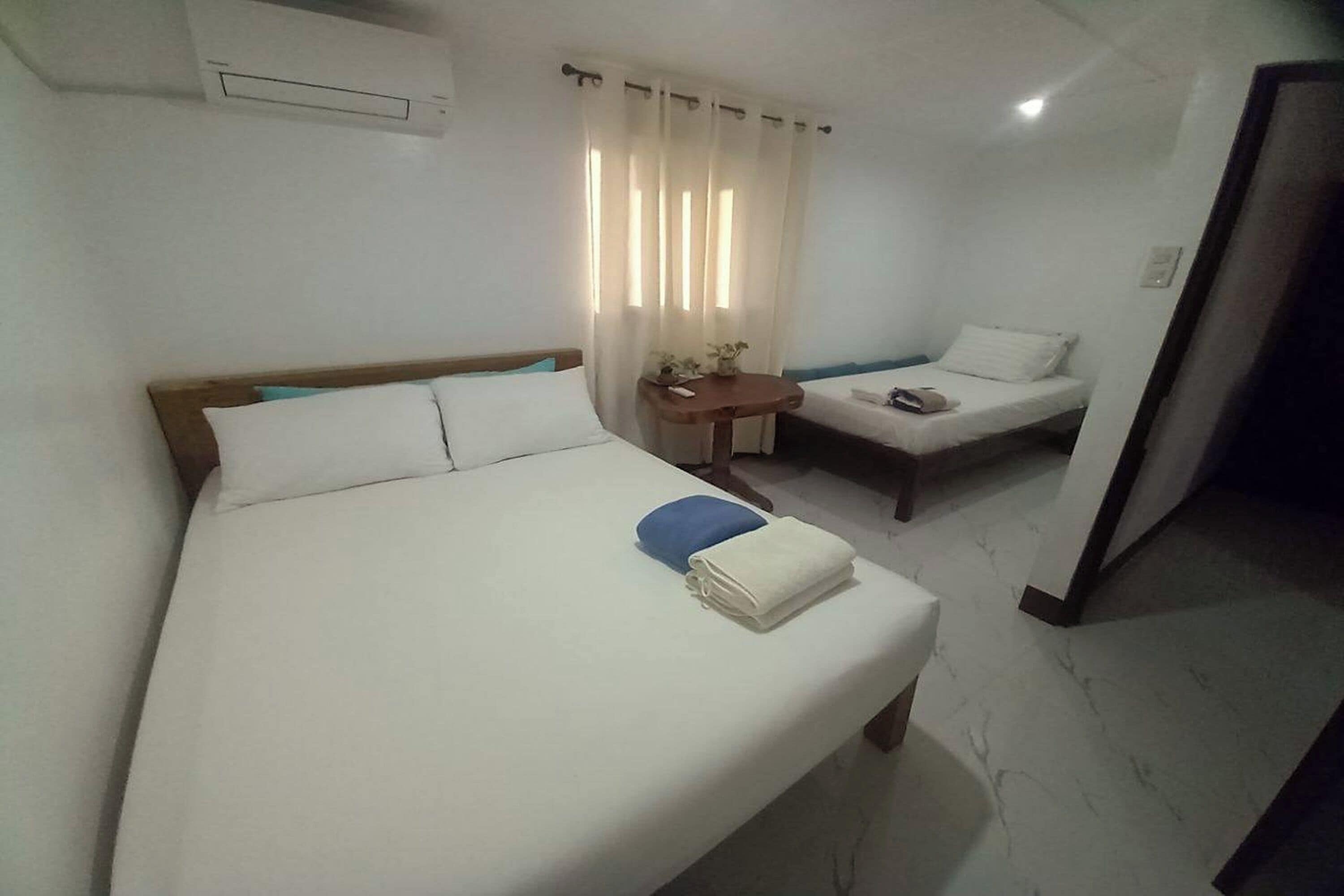 Una habitación de hotel con una cama grande, una cama más pequeña, un escritorio y una silla.