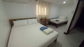 Una habitación de hotel con una cama grande, una cama más pequeña, un escritorio y una silla.